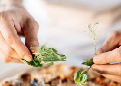 Chef placing herb on pizza